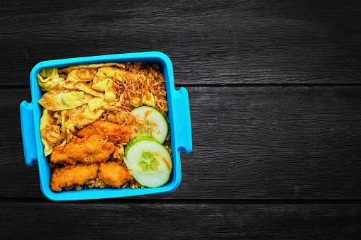 lunch box contained of fried rice, nuggets on ceramic table