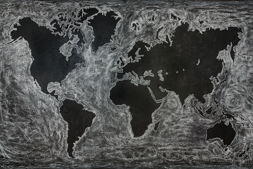 World map mural with white chalks on a blackboard wall in the room