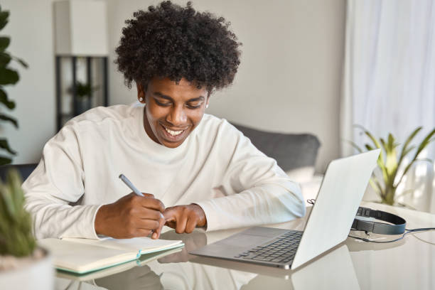 istock Happy African American teen student elearning at home on pc, writing notes. 1500830802