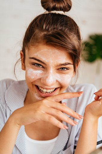 Young  woman doing routine skin care at home with beauty products