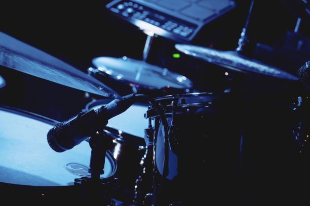 istock Microphone is suspended above a drum kit in a dimly lit room 1500833711