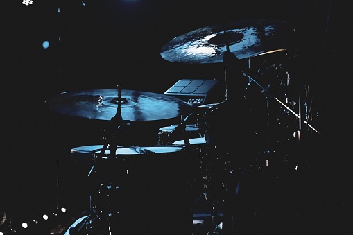 A closeup of drums in a dimly lit room with spotlights illuminating the stage