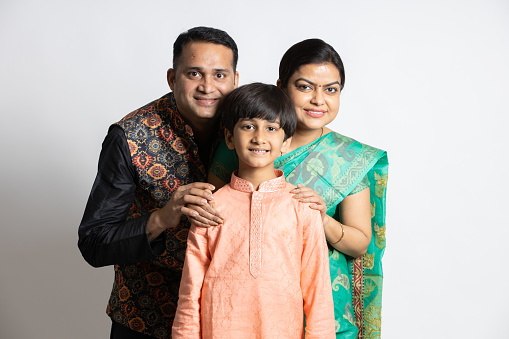 Happy young indian parents with their little son wearing ethnic festive outfit isolated over white background. Smiling asian family. Father and mother with boy chil.