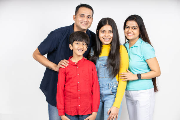 istock Happy young attractive indian family looking at camera isolated on white studio background. Smiling urban asian parents standing with teenager daughter and little son. 1500837586
