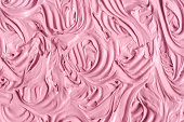 Rose cosmetic clay (make-up blusher, lipstick, alginate facial mask, berry body wrap) texture close-up, selective focus. Abstract background with swirl brush strokes.