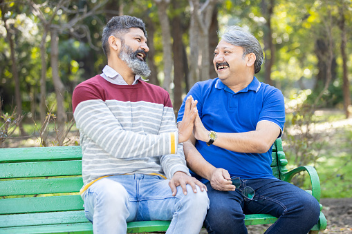 Two happy indian Mature senior men having fun at park outdoor, Asian friends enjoy life, retirement and life insurance concept.