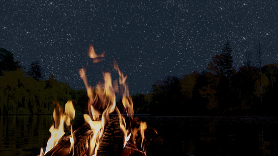 a bonfire burns at night against the background of mountains and sea with bright stars