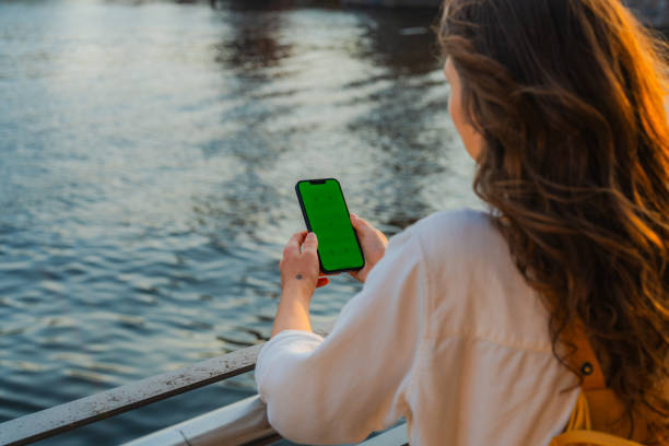 istock Woman using smartphone standing on the bridge over the river 1500846681