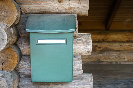 A woman is collecting post at home in autumn, Quebec, Canada. She is smiling and unlocking the mailbox. She is pickup-up her mail and looking at the letters she received.