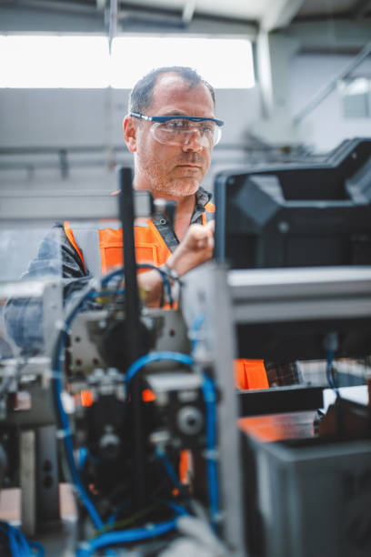 concentrato e diligente: dipendente maschio professionista che testa e controlla i cavi delle apparecchiature industriali nel magazzino della fabbrica di elettronica - laboratory service electricity scientific experiment foto e immagini stock