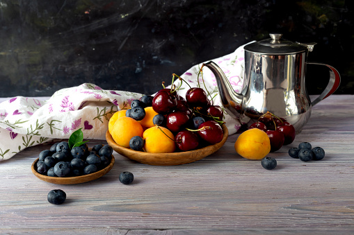 Fruits. Apricots, cherries and blueberries lie in plates on a wooden table close-up