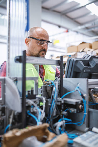 istock Focused and Diligent: Professional Male Employee Testing and Checking Industrial Equipment Cables in Electronics Factory Warehouse 1500849484