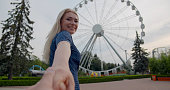 Pov shot of man holding hand with young girlfriend in amusement park. Follow me concept