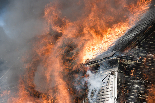 Residential home fully engulfed in fire (close-up of side and roof)