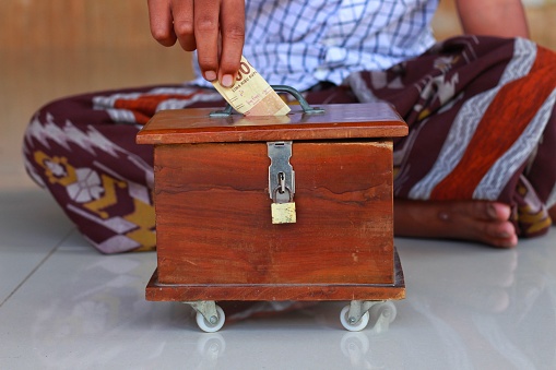 Infaq, an asian child hand put money, Indonesian Rupiah, in a charity box for donation