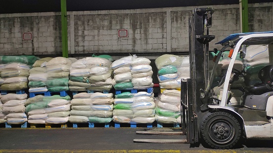 White forklift next to several pile of wet shredded coconut cover with plastic after production process in the factory