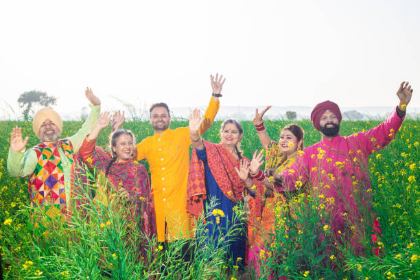 famiglia sikh punjabi che fa danza bhangra nel campo agricolo che celebra baisakhi o vaisakhi festival. - bhangra foto e immagini stock