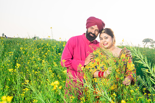 Portrait of Happy young Punjabi sikh couple standing together at agriculture field.