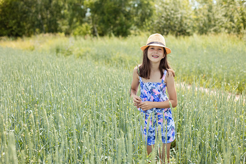 Close-up portrait of a pretty teenage girl wearing a hat in a summer park at sunset, copy space.