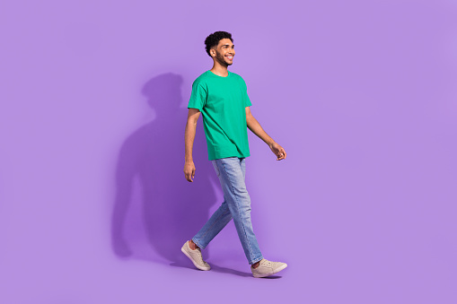 Full body photo of young man steps satisfied stylish casual clothes shopping offer purchase cheap look isolated on violet color background.
