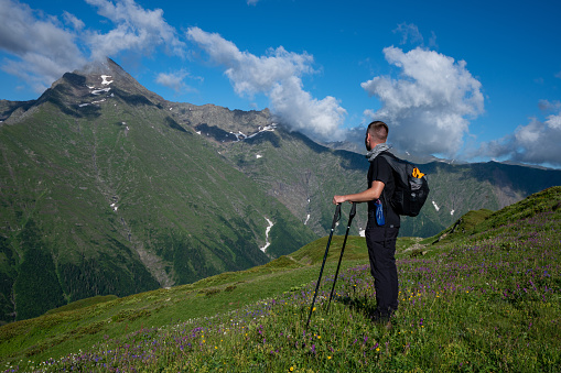 On the walk in the mountains. Hiker enjoys a view on mountain peak.