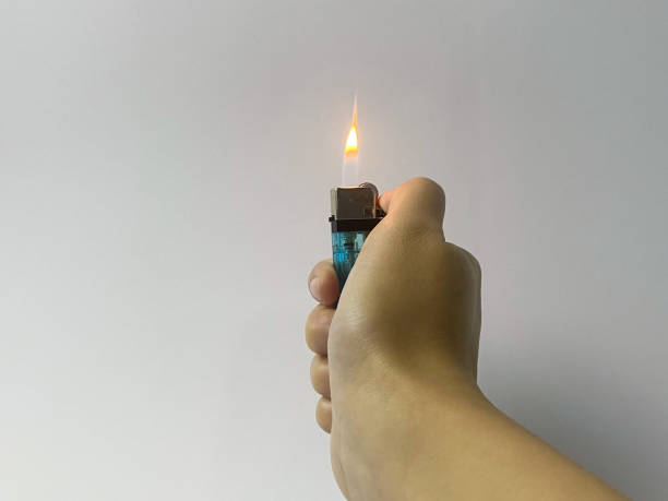 istock Cropped hand of a woman's hand turning on a lighter on white background. 1500856574