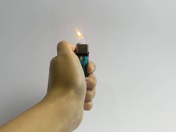 istock Cropped hand of a woman's hand turning on a lighter on white background. 1500856592