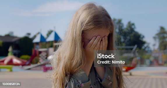 istock Caucasian preschool girl crying alone on playground at park. 1500858134