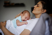 Exhausted mother holding her crying newborn baby. Postpartum depression.