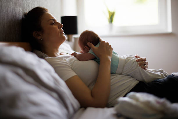 Exhausted mother holding her crying newborn baby. Postpartum depression. - fotografia de stock