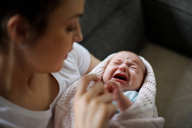 Bambino appena nato che piange nelle mani della madre - foto stock