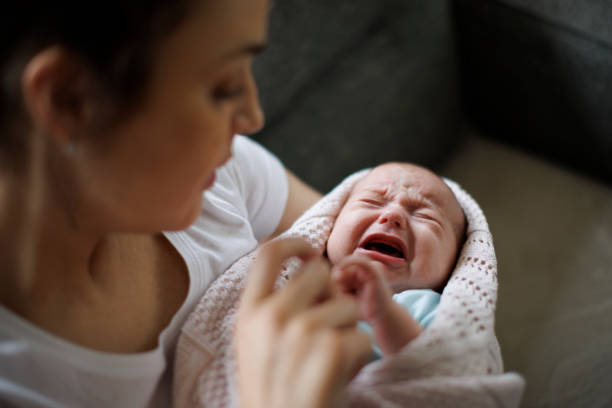 Newborn baby crying in mother's hands stock photo