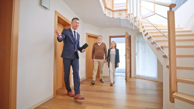 Male real estate agent showing a modern house to a senior couple