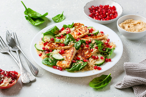 healthy halloumi cheese and couscous salad with cucumber spinach pomegranate hummus