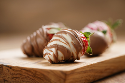 chocolate covered strawberries on wood board, shallow focus