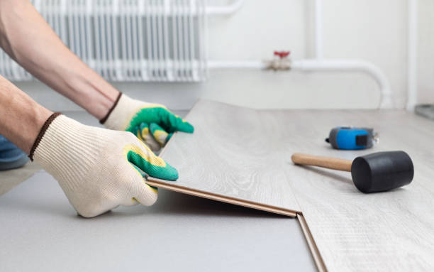 Man in protective gloves lays a laminate on the floor.