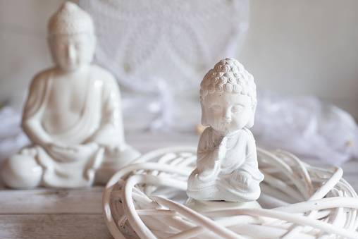 white Buddha figurine in white ambience with atmospheric lighting