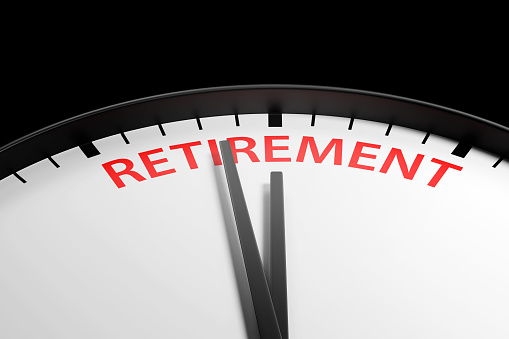 Hour and minute hands are almost pointing to the centre of the word RETIREMENT printed on a round black clock. Illustration of the concept the retirement age is going up