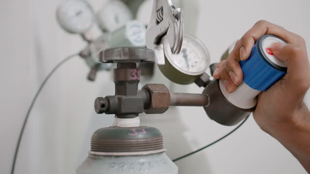 A scientist installing a nitrogen pressure gauge valve on cylinders in a specialized laboratory