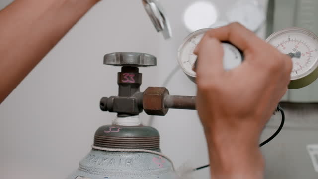 In a specialized laboratory, a scientist installs a nitrogen pressure gauge valve on cylinders.