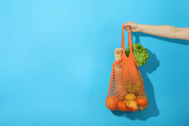 istock Female hand holds string bag with grocery on blue background 1500886234