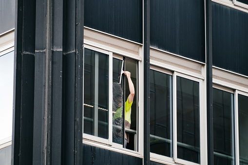 An unrecognizable window cleaner cleaning the windows of an office building