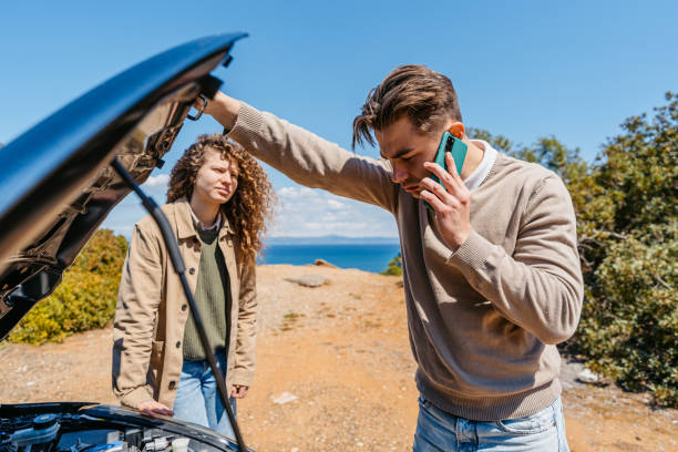 Couple On A Vacation Having A Car Breakdown And Calling For Assistance Couple on a vacation having a car breakdown and calling for assistance. tow truck stock pictures, royalty-free photos & images