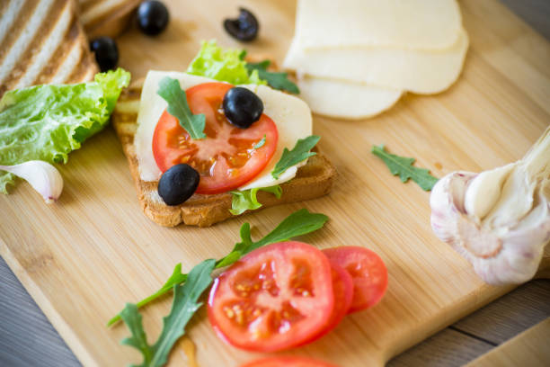 fried toasts with mozzarella, lettuce and tomatoes with herbs stock photo