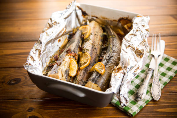 Baked fish with seasonings and spices in foil stock photo