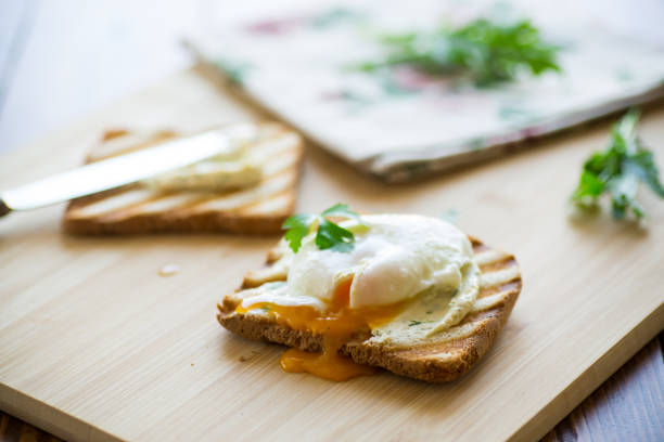 pain grillé frit avec œuf poché et étalé, sur une table en bois. - sandwich breakfast boiled egg close up photos et images de collection