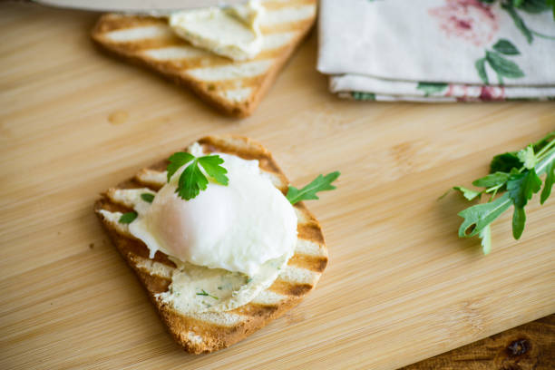 pain grillé frit avec œuf poché et étalé, sur une table en bois. - sandwich breakfast boiled egg close up photos et images de collection