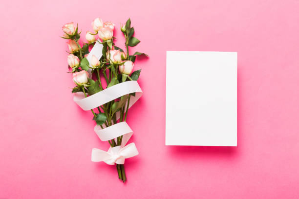 istock Greeting holiday card mockup with fresh roses on colored table background, mock up with copy space for design 1500897225