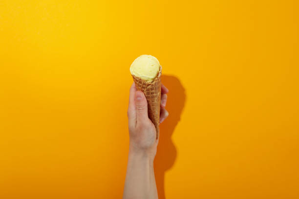 istock Female hand holds ice cream on orange background 1500903061