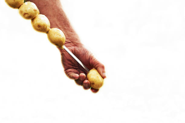 istock Hands of a man stringing potatoes on a skewer for grilling on white 1500903859